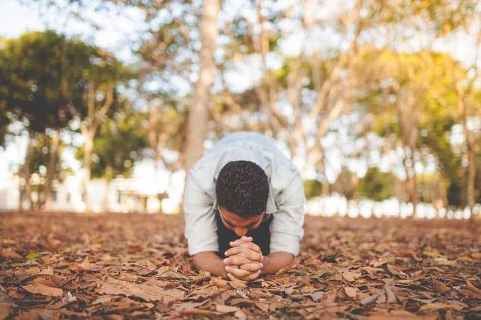 man praying on knees and elbows 