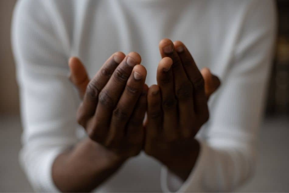 Man with hands together and open to illustrate praying. 