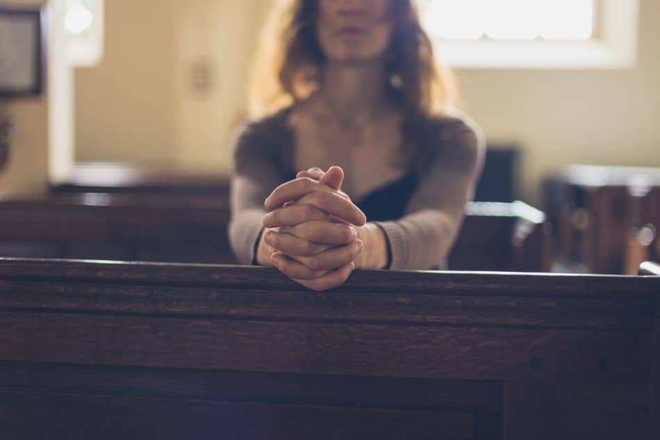 Person in pew hands folded 