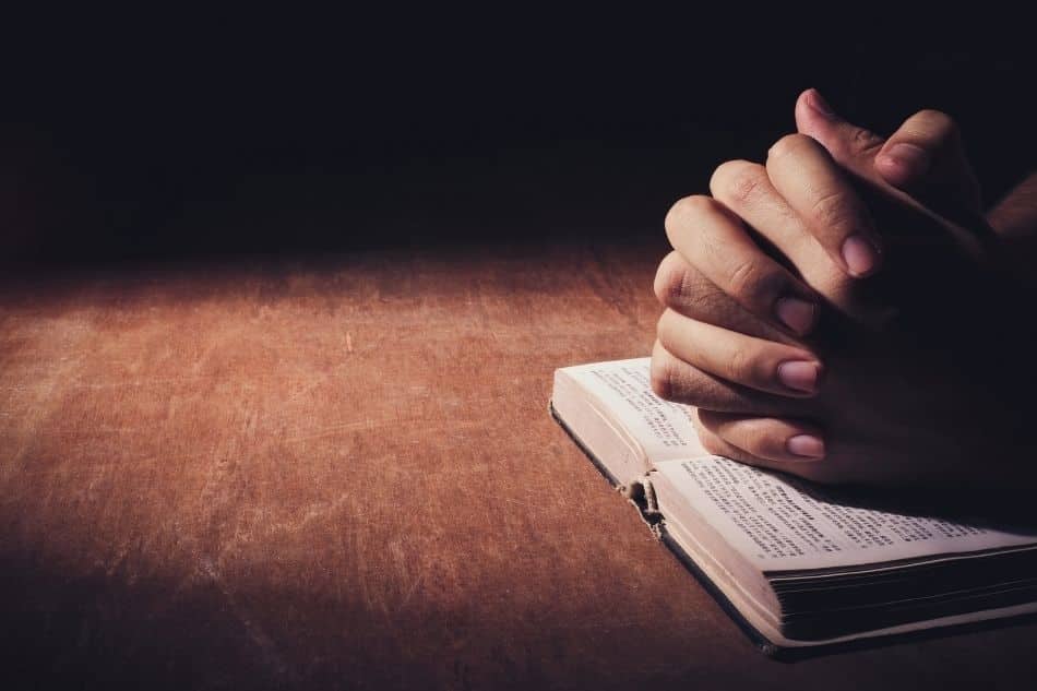 hands folded on Bible