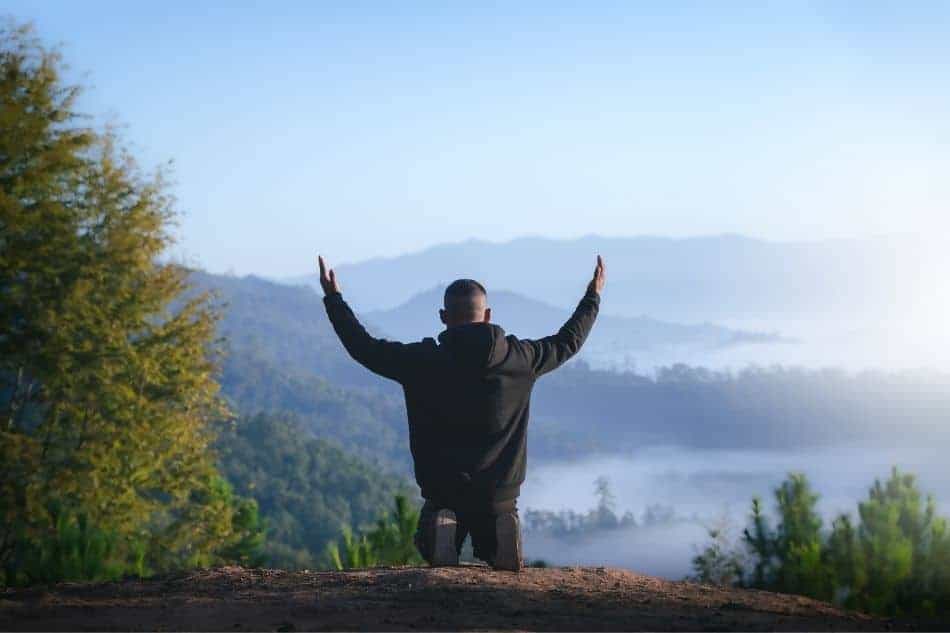 man praying overlooking forest