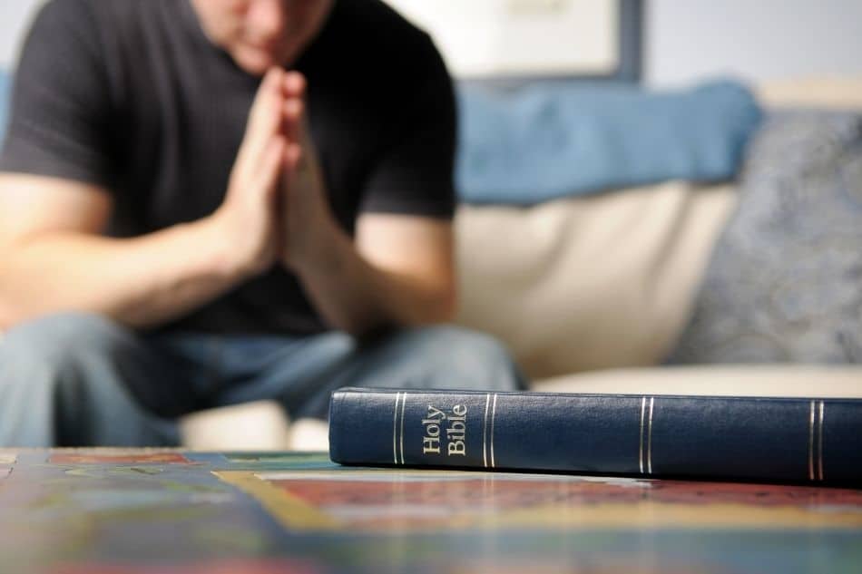 Man praying next to Bible