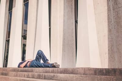 man laying on top of cement steps in front of building