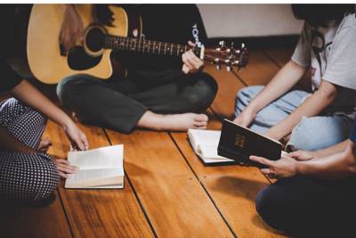 people sitting on floor with guitar and bibles open