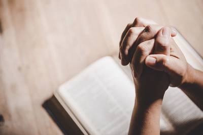 hands folded above Bible