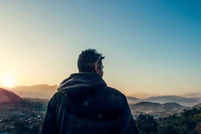 man overlooking view of town with a rising sun in the background