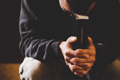 man praying with Bible in his hands