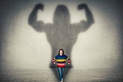 women standing with muscular and big shadow behind her