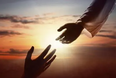 hands reaching to each other with sun in the background