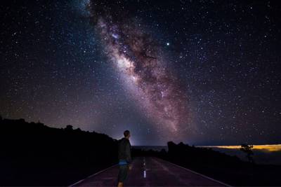 man looking up in space while standing on road