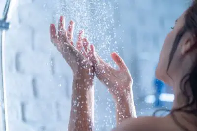 women in shower holding hands up to the water