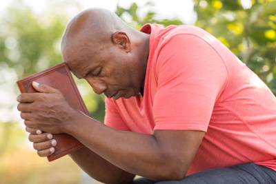 man with bible in hand praying