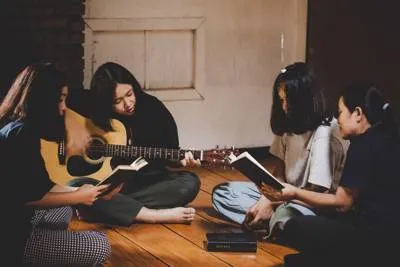 group of people sitting on the floor with a guitar and a bible