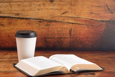 Open Bible next to a coffee cup indicating a Bible Study taking place.