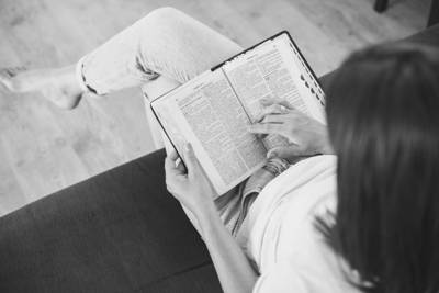 person sitting on the couch reading their bible